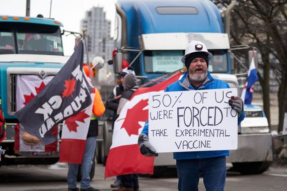 Man holding a sign which says "50% of us were forced to take experimental vaccine"